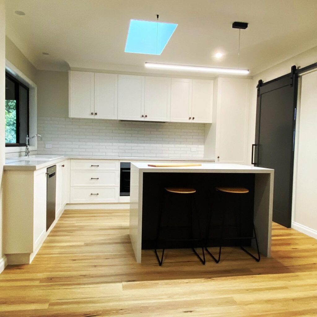 Modern white kitchen with island and skylight
